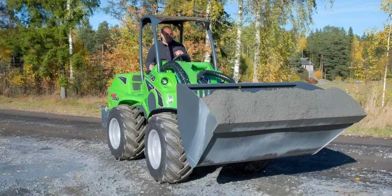 A man driving a green loader for property maintenance